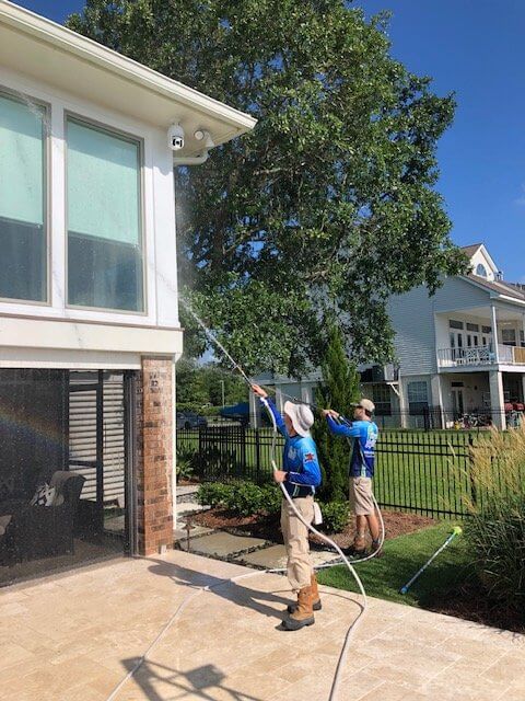 Pelican SoftWash professionals cleaning windows on brick home