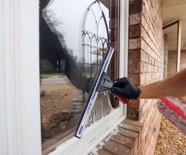 cleaning professional with black gloves cleaning residential window
